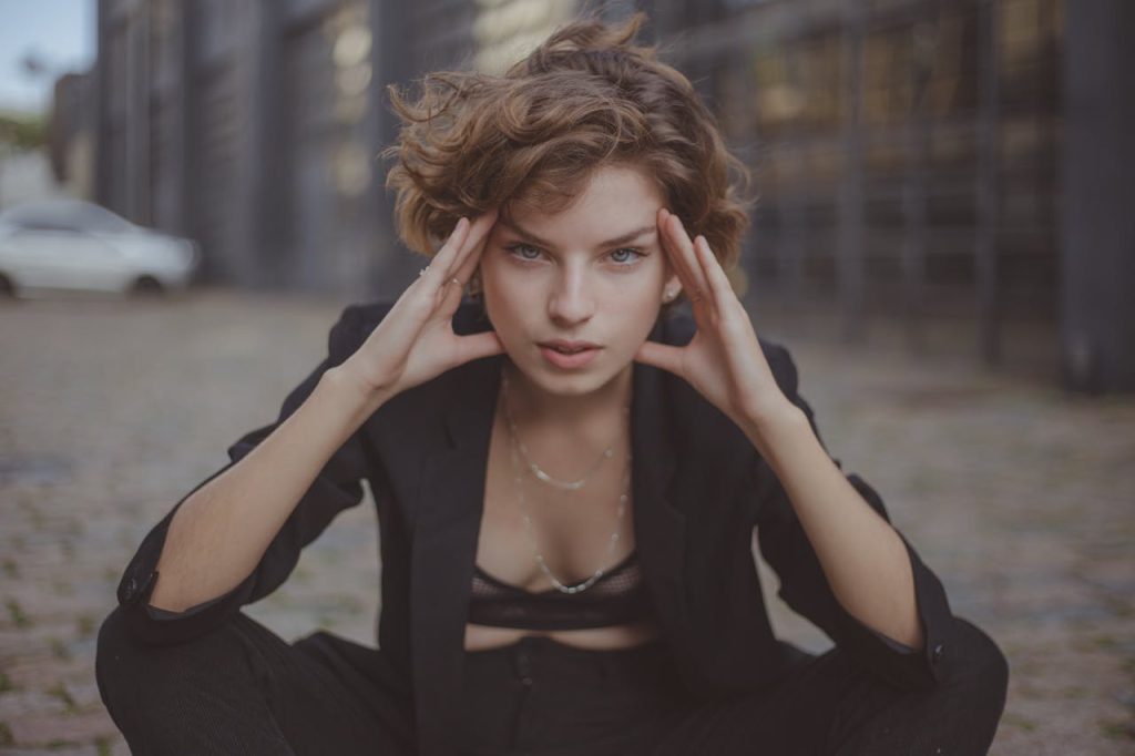 A fashionable woman posing in a modern urban street setting.